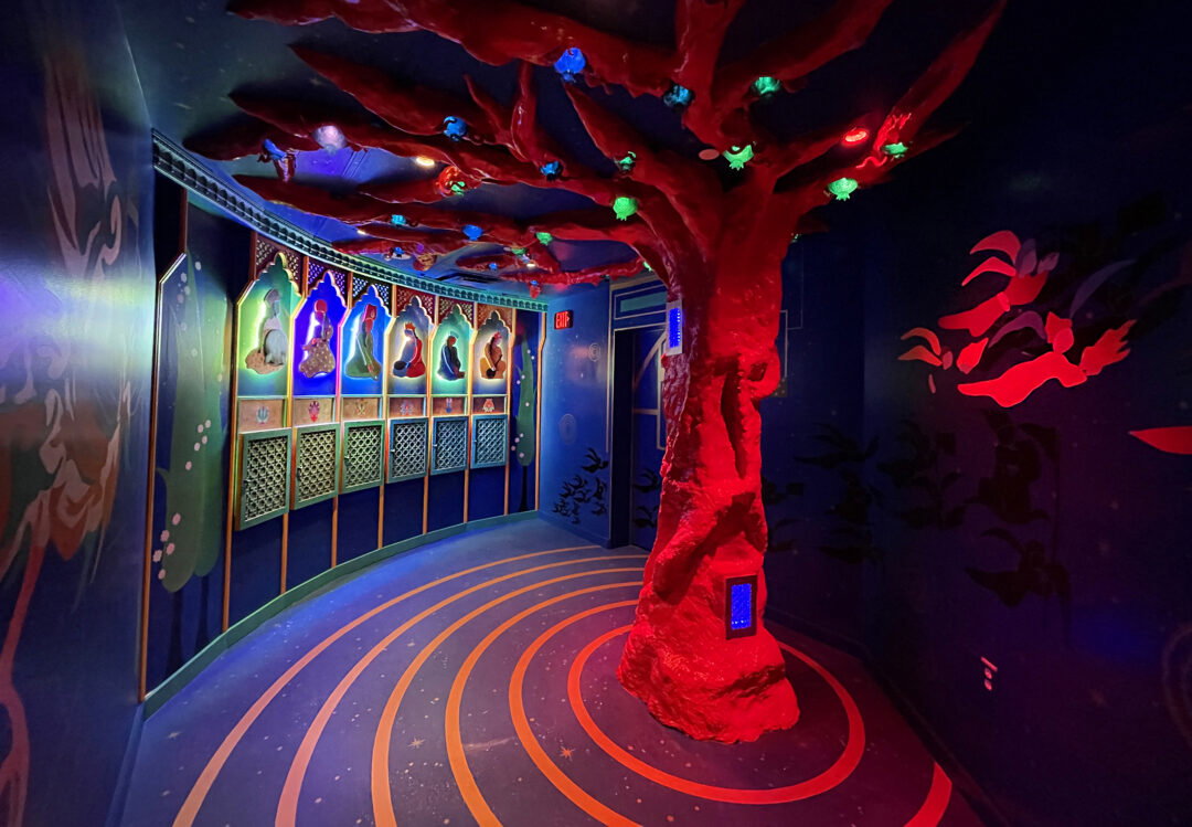 A calm blue room with a tree full of pomegranates and Persian portraits.