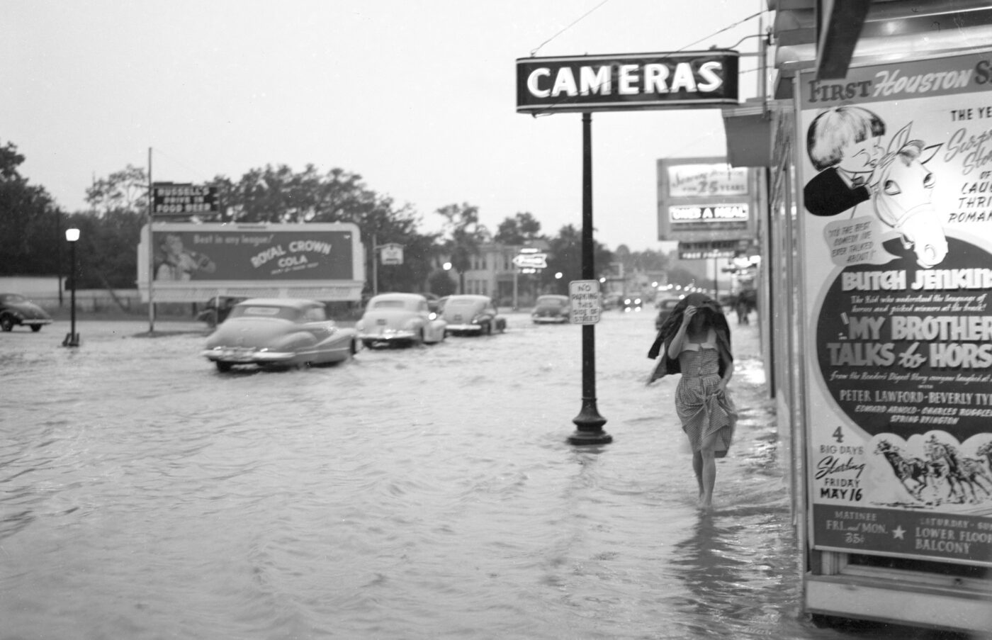 A woman takes shelter beneath her coat during a 1947 storm that flooded Richmond Avenue at South Main outside the Delman Theater.