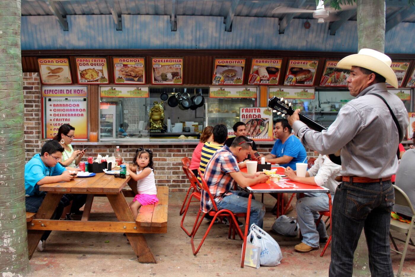 A mariachi serenades diners eating corn dogs and burritos from a kitchen that sports a fat, gold Buddha.