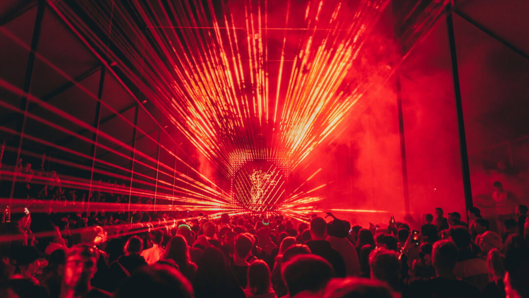 People dancing under flashing geometric red lights