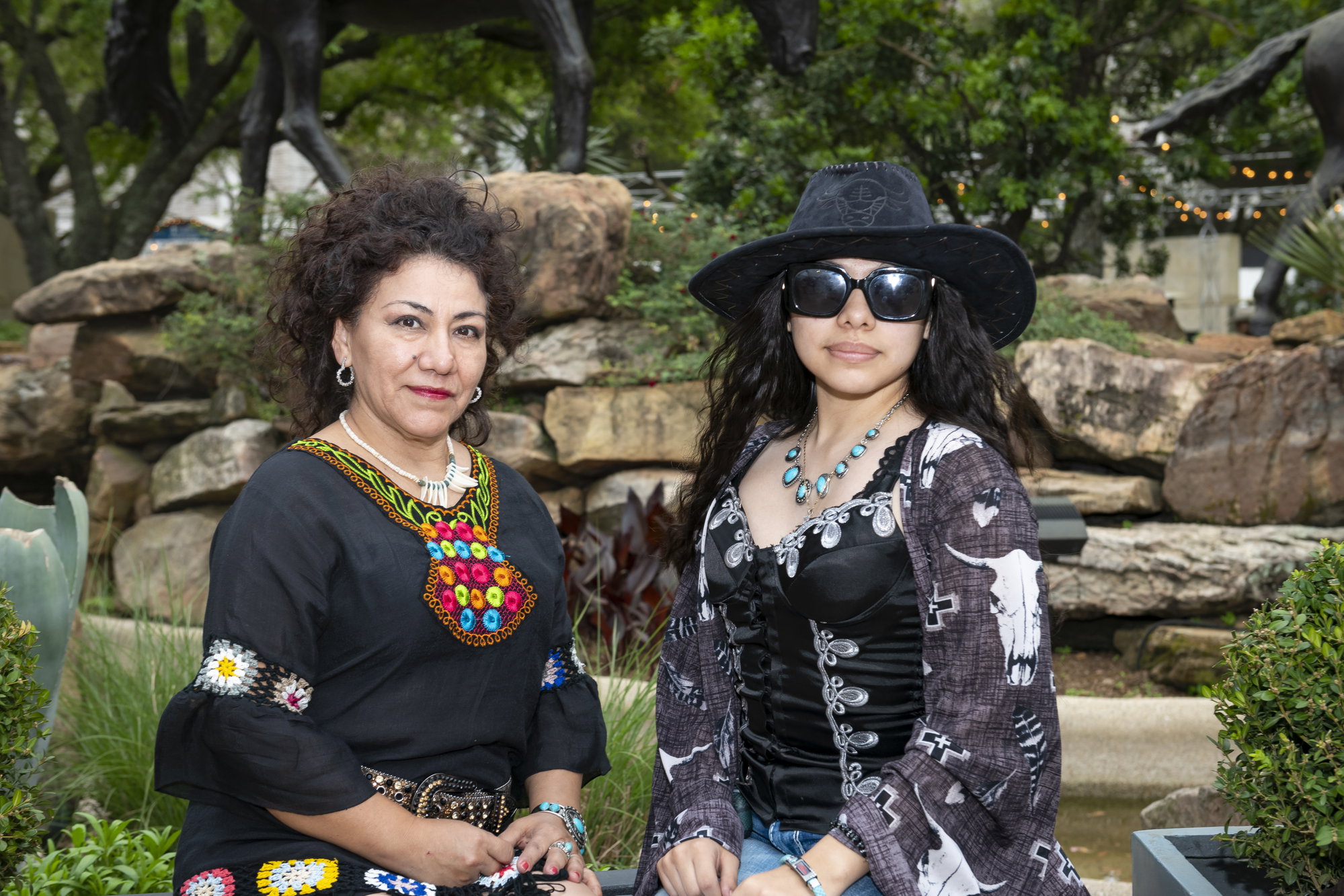 A mother and daughter pose for a picture wearing floral and western-style prints.